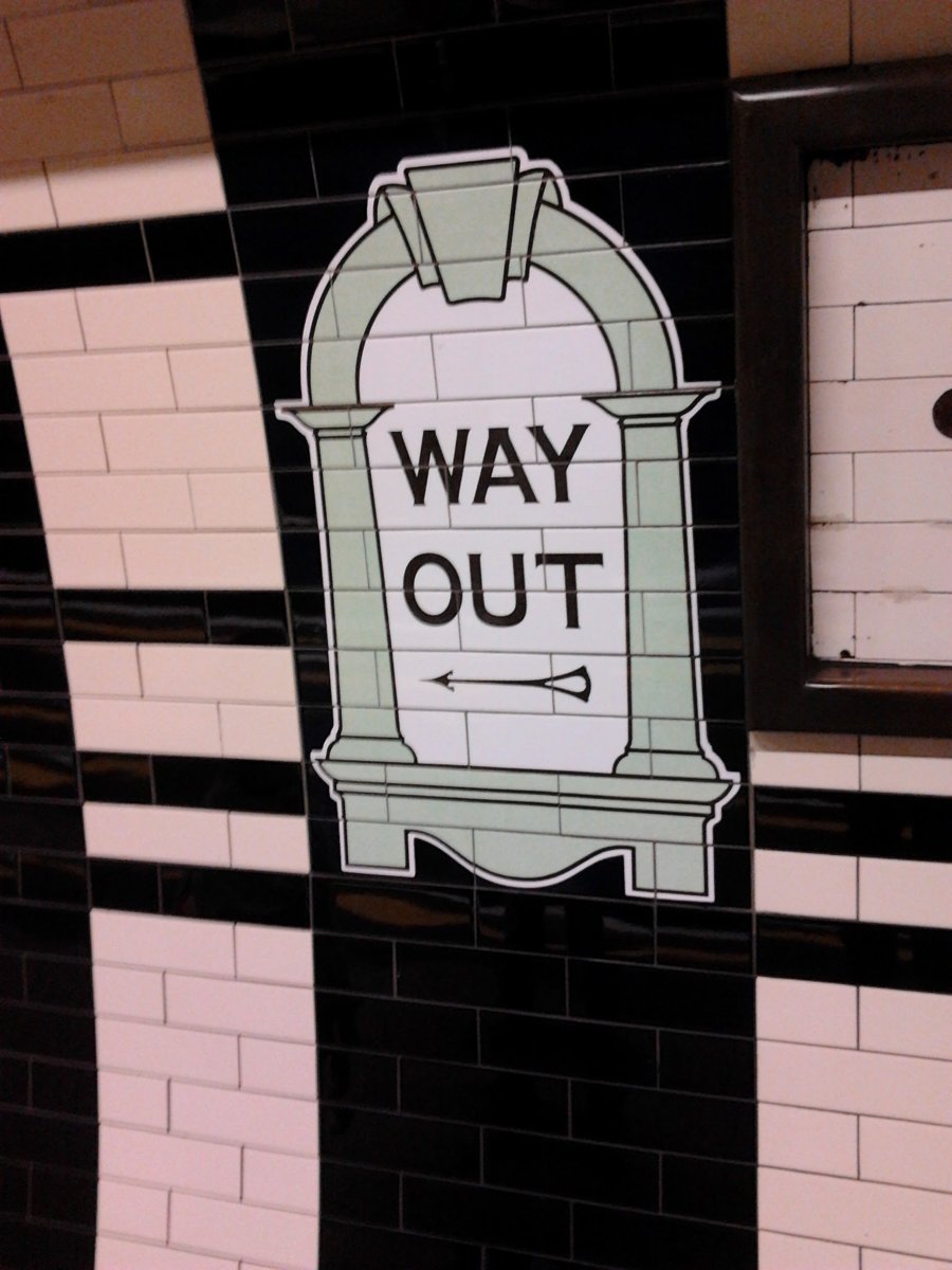 Panneau Way Out sur un mur carrelé du métro londonien